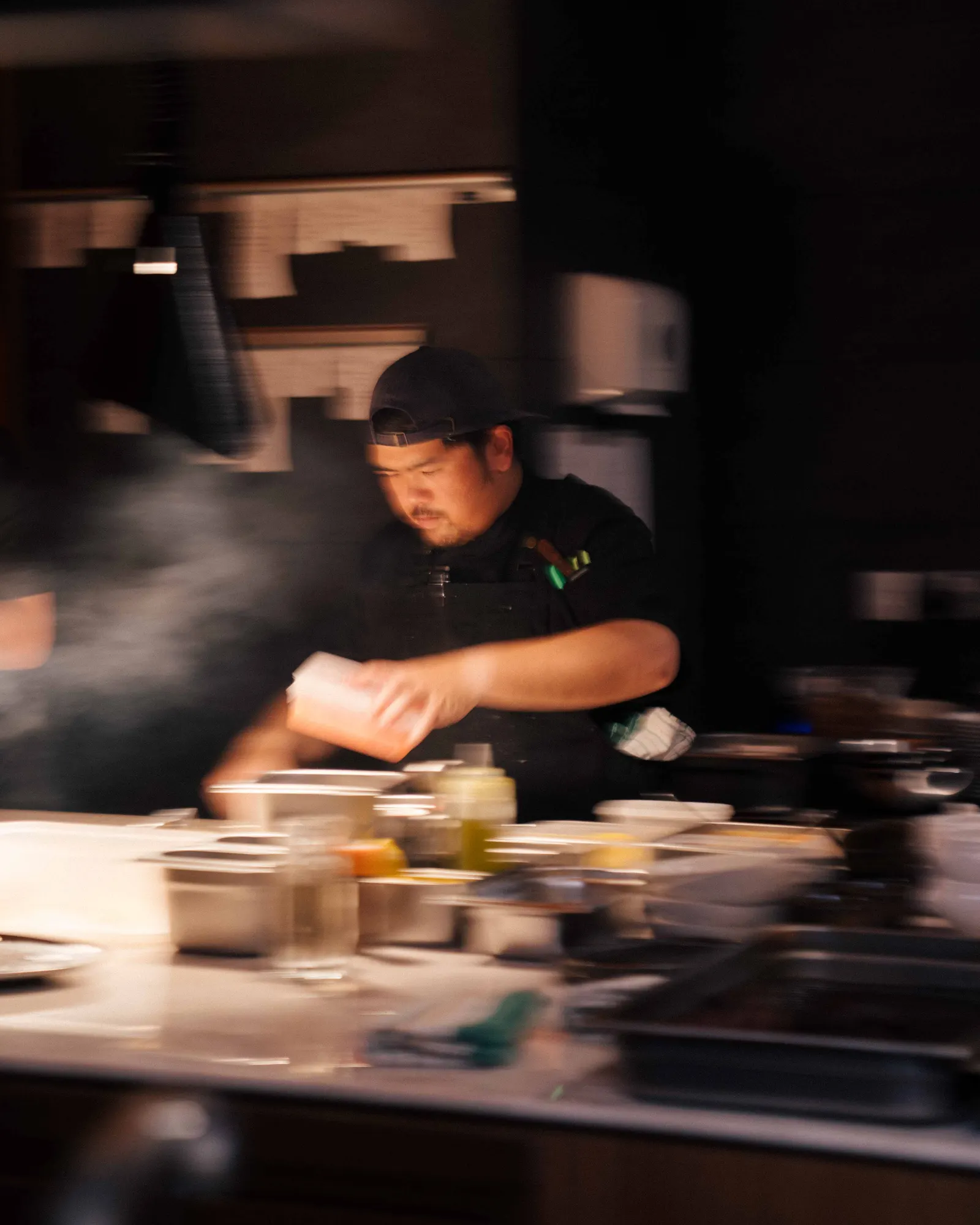Chef plating a dish at the kitchen pass, in motion blur